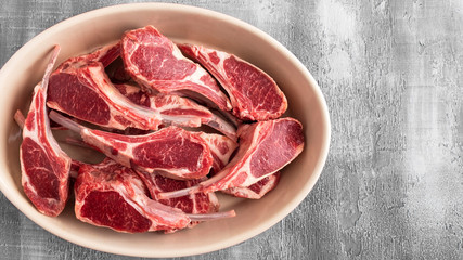 Raw lamb meat ribs on a plate with copy space. Top view.