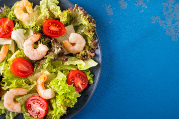 Shrimp salad with tomatoes and mixed greens on a plate. Top view. Copy space