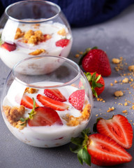 Strawberry in yogurt with muesli in a glass bowl. Healthy and diet food. Closeup