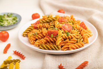 Tortiglioni semolina pasta with tomato and microgreen sprouts on a white wooden background. Side view, selective focus.