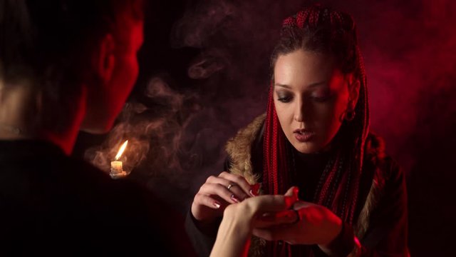 Fortune teller with braids predicting future by hand to woman