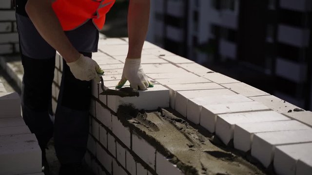A bricklayer makes a wall of white brick