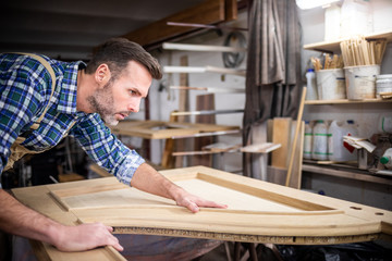 Carpenter working on wooden door in his workshop