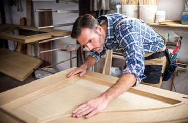 Carpenter working on wooden door in his workshop