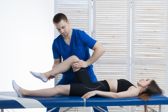 The Orthopedic Doctor Makes A Diagnosis Of The Muscle Tone On The Girl's Legs. Manual Therapy