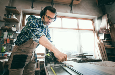 Carpenter using woodworking tools for craft work in carpentry workshop