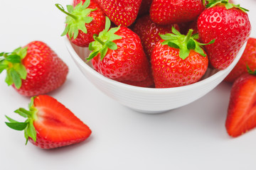 Red ripe strawberry in the white bowl, light background