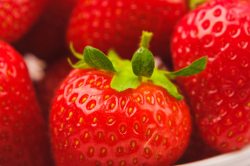Red ripe strawberry in the white bowl, light background