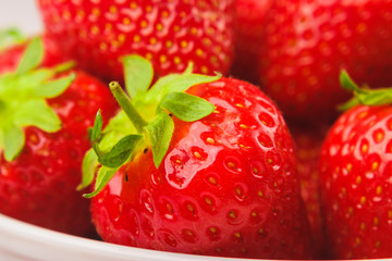 Red ripe strawberry in the white bowl, light background