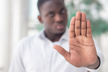 black African business man showing stop, halt hand gesture; concept of forbidden act, rejection,...