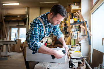 Carpenter using woodworking tools for craft work in carpentry workshop