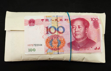 thick envelope with chinese money on a black background.