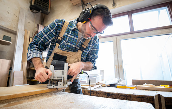 Carpenter using woodworking tools for craft work in carpentry workshop