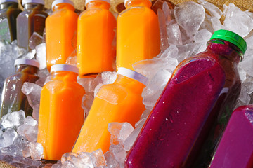 Bottles of colorful cold pressed juice on ice