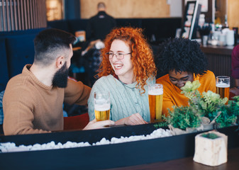 Three friends hanging out in the bar laughing and joking around.