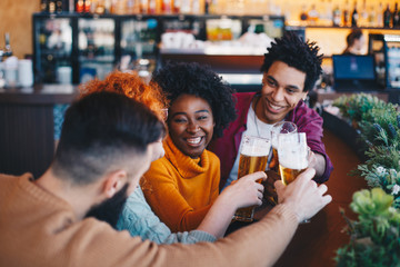 Three friends hanging out in the bar laughing and joking around.