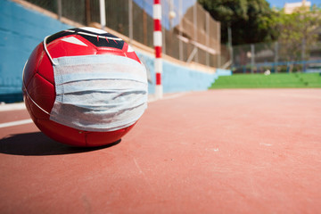 Soccer and coronavirus concept, soccer ball with respiratory mask on soccer field closed to the public, space to write