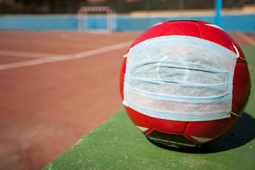 Soccer and coronavirus concept, soccer ball with respiratory mask on soccer field closed to the public, space to write