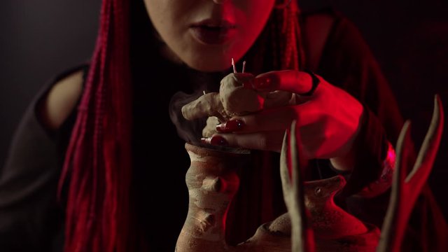 Partial view of woman holding voodoo doll over steaming vessel