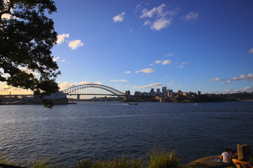 Sydney Harbour bridge on a warm summer afternoon at Sunset blue skies and white orange clouds