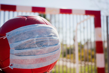 Soccer and coronavirus concept, soccer ball with respiratory mask on soccer field closed to the public, space to write