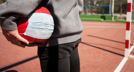 coronavirus concept, young boy with soccer ball, wearing respiratory mask soccer field without children