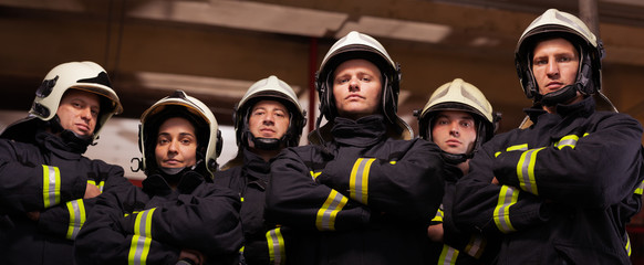 Group of six professional firefighters standing together. Firefighters wearing uniforms and...
