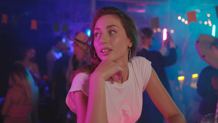 Portait of sad enchanting young woman in fashion look at bar counter looking around being lonely at youth night party in the club.