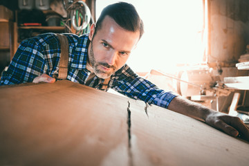 Carpenter checking if the wooden board is flat and even
