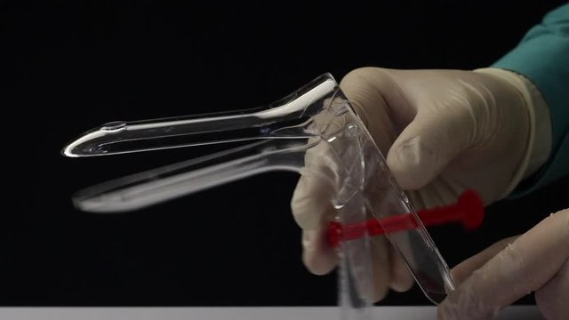 A doctor in rubber gloves shows a one-time gynecological mirror. Gynecological speculum Cusco. Close-up shot..