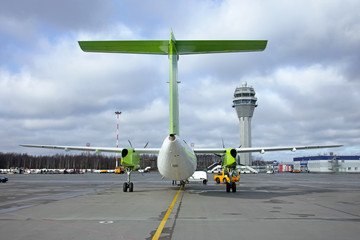 Turboprop aircraft parked at the airport against the background of the Atc control tower.