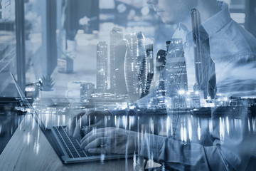 e-commerce and internet technology double exposure, hands typing on keyboard against city skyline