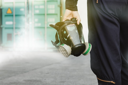 Male Industrial Technician Who Holds A Respirator Mask, An Ammonia Odor Mask, NH3 To Control And Fix Leaks Inside The Factory's Container : Copy Space