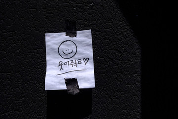 Hand draw cartoon with paper note stickers on wall ,the korean word means smile