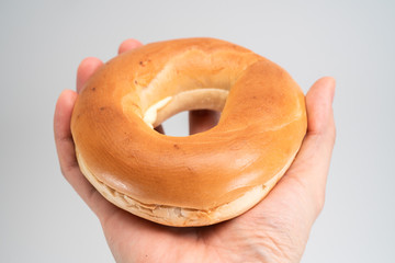 Fototapeta na wymiar Ring bread (bagel) in hand isolated on white