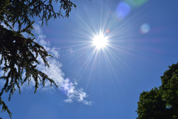 Fototapeta premium Sun at zenith at noon in blue sky with little clouds