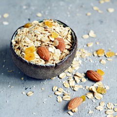 Home granola in a bowl. Selective focus. Healthy vegan snack. Granoll morning breakfast with almonds, raisins, dried cranberries on a blue (gray) background. Healthy eating concept