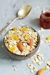 Home granola in a bowl. Selective focus. Healthy vegan snack. Granoll morning breakfast with almonds, raisins, dried cranberries on a blue (gray) background. Healthy eating concept
