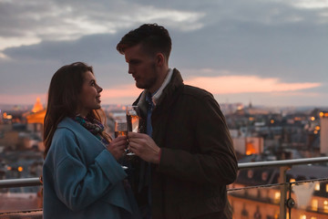 dating, young couple drinking champagne in Paris by night, cheers on rooftop terrace of luxury...