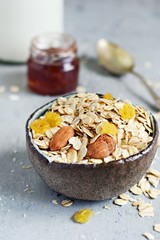 Home granola in a bowl. Selective focus. Healthy vegan snack. Granoll morning breakfast with almonds, raisins, dried cranberries on a blue (gray) background. Healthy eating concept