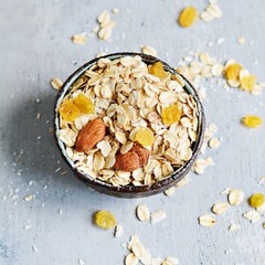 Home granola in a bowl. Selective focus. Healthy vegan snack. Granoll morning breakfast with almonds, raisins, dried cranberries on a blue (gray) background. Healthy eating concept