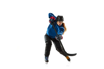 Young female hockey player with the stick on ice court and white background. Sportswoman wearing equipment and helmet training. Concept of sport, healthy lifestyle, motion, action, human emotions.