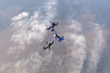 Skydiving. Three skydivers are in the sky above white clouds.