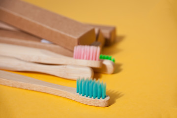 Four eco bamboo kid colorful toothbrushes on the yellow background