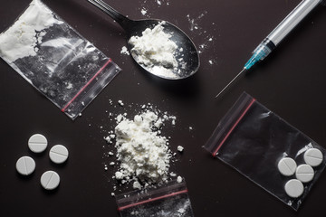 White powder drugs, prescription drugs, syringe on dark table. overhead 