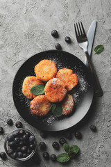 Breakfast of cheese pancakes on grey background, top view