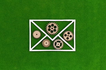 Envelope for a letter, wooden gears on a green background. Reporting information.