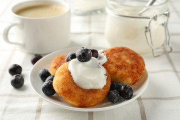 Plate with cheese pancakes on kitchen towel background, close up
