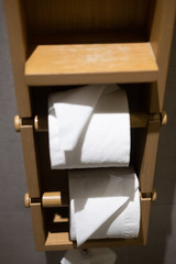 Roll of white toilet paper on wood paper holder
