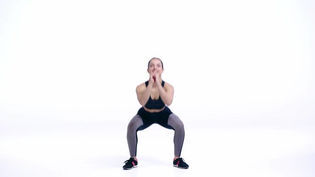 happy sportswoman doing squat exercise on white